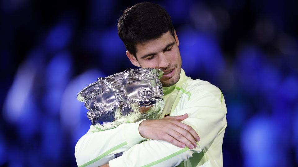 Carlos Alcaraz hugs the Australian Open trophy