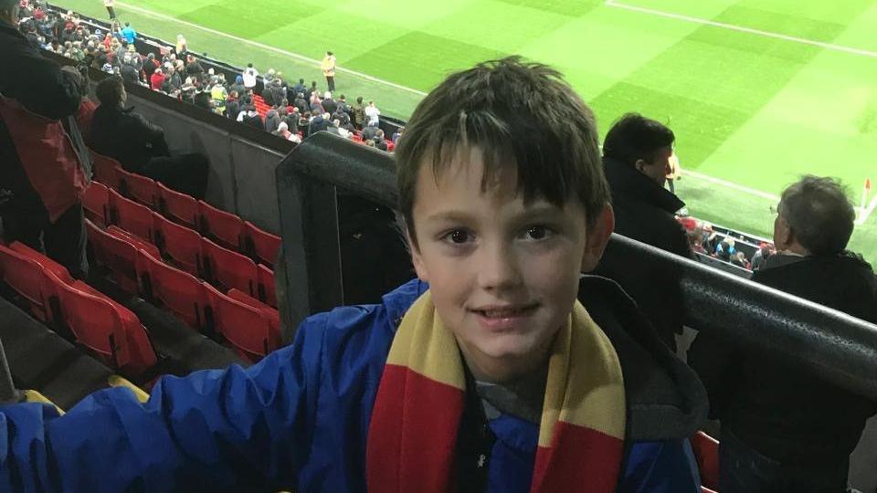 A young Christopher McBurnie wearing a red-and-white Liverpool scarf in the stands at Anfield.