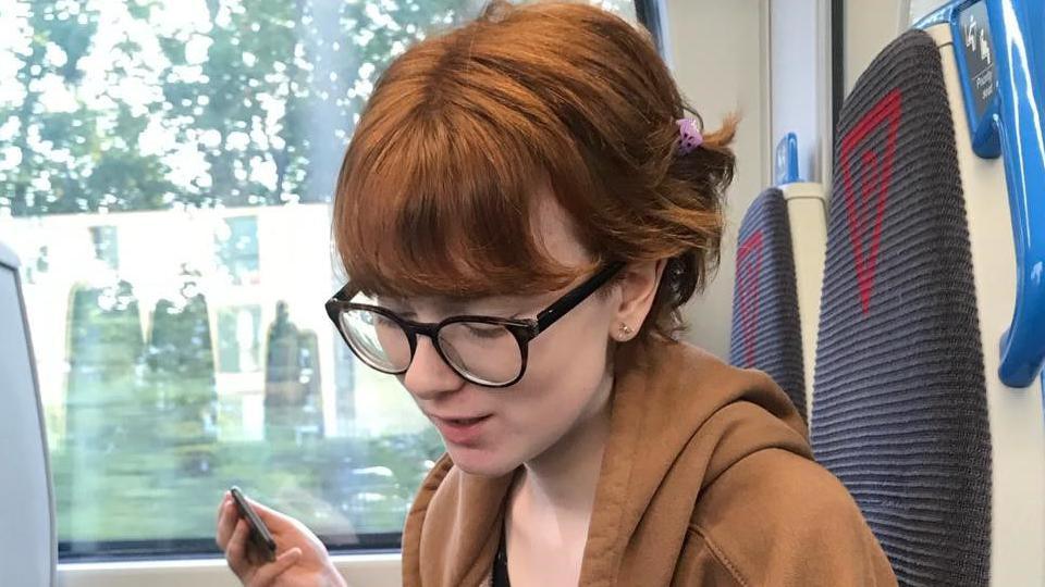 A young woman on the train looking down at her lap