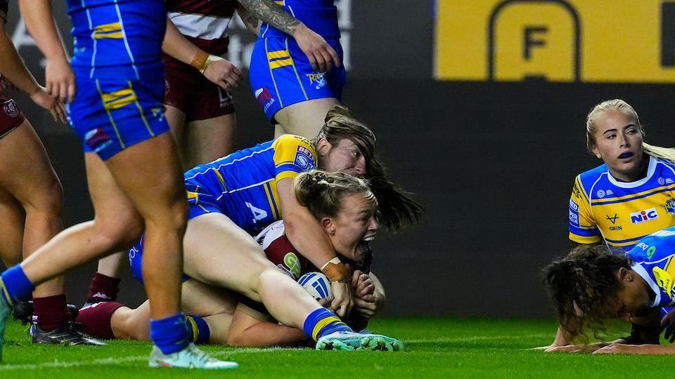 Mary Coleman celebrating her second try of the match with her mouth open while on the line with the ball.