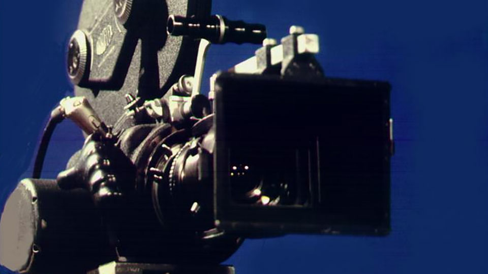 A film camera in front of a blue background.