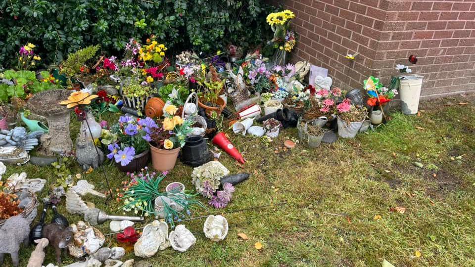 Numerous small items including plants, flowers and figurines on grass