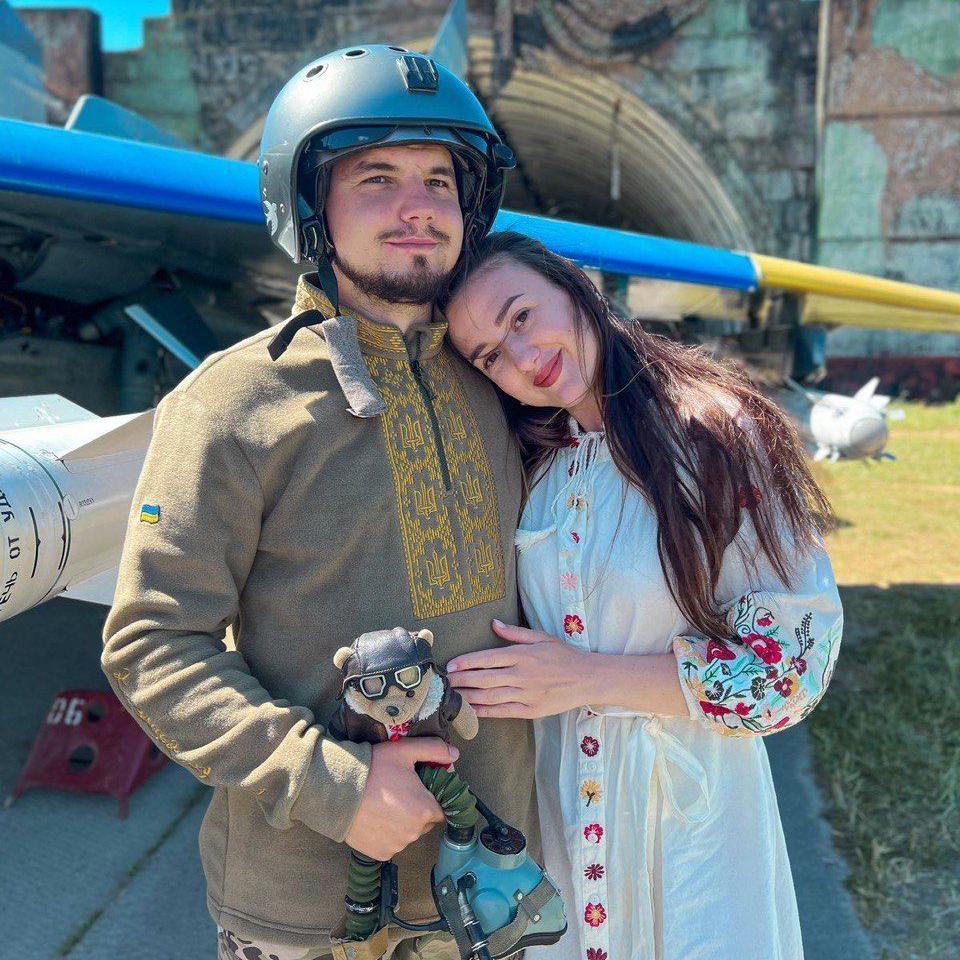 Ivan, a 31-year-old Ukrainian man wearing a helmet, standing in front of an aircraft with his wife Maria, 29