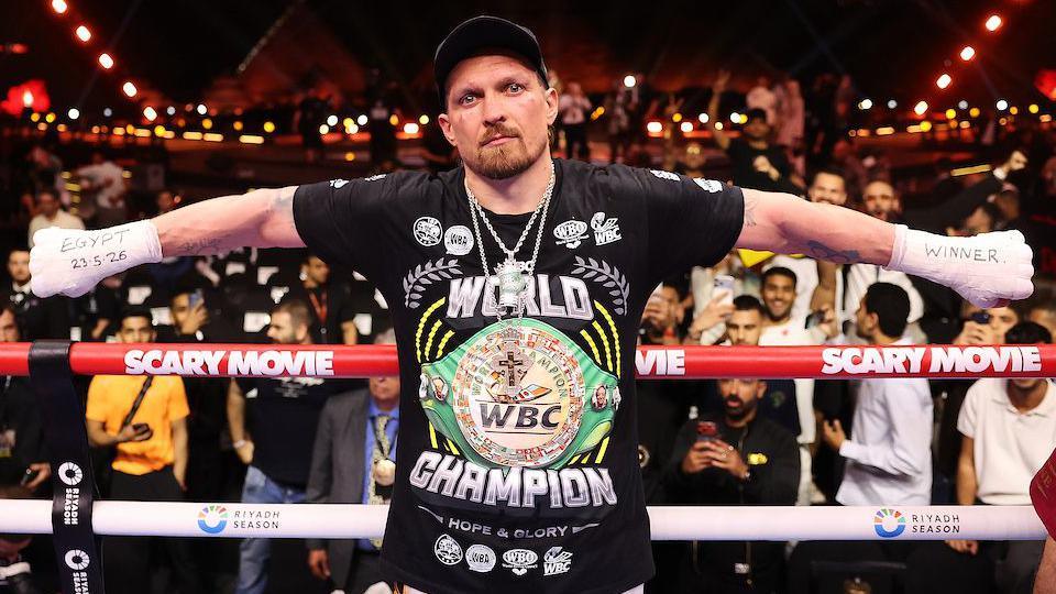 Oleksandr Usyk with his arms outstretched and 'Egypt 23.5.26' written on his right hand and 'winner' written on his left hand