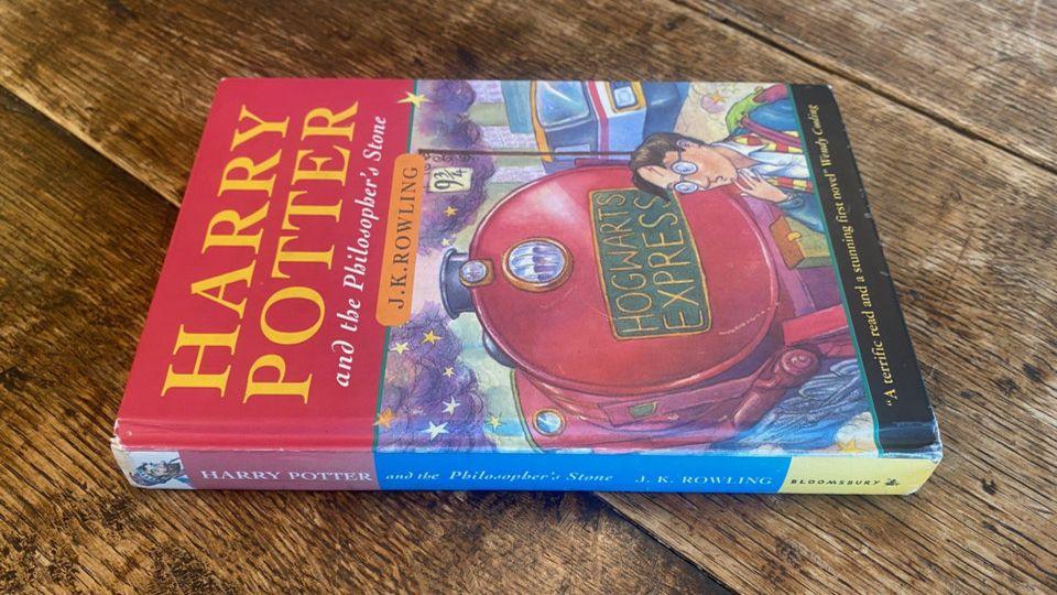 A Harry Potter hard back book is pictured on a wooden table.