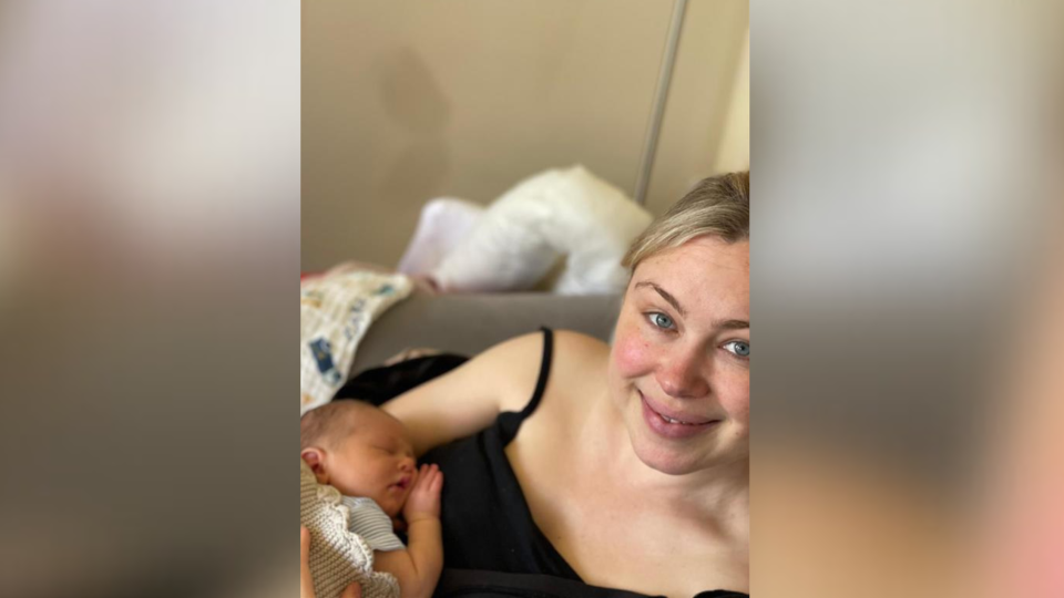 Cornelia Marland wearing a black strappy top and holding her new baby against her chest.