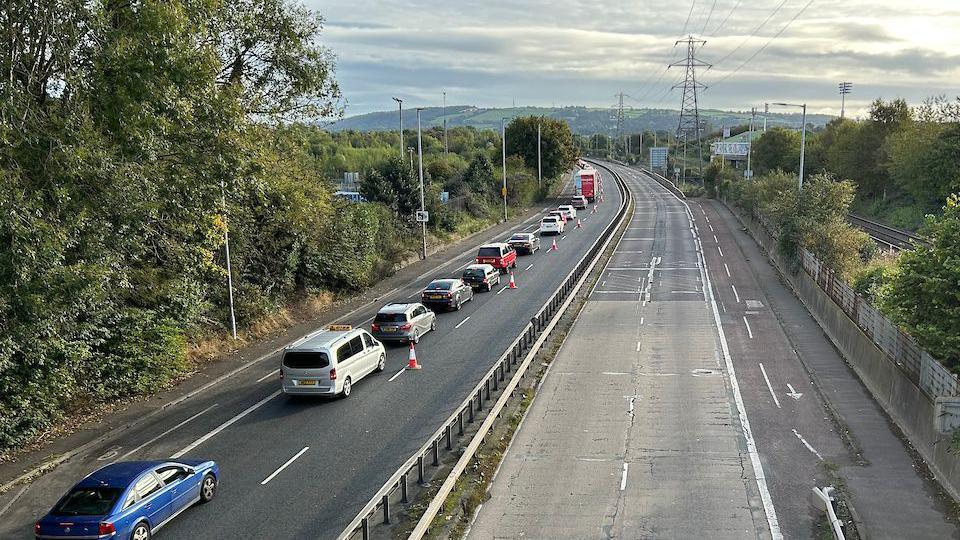 An aerial shot of the dual carriageway which has one lane of long traffic. The other side has no cars for the work to begin.