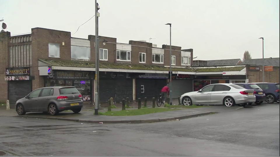 A row of run down shops with cars parked outside