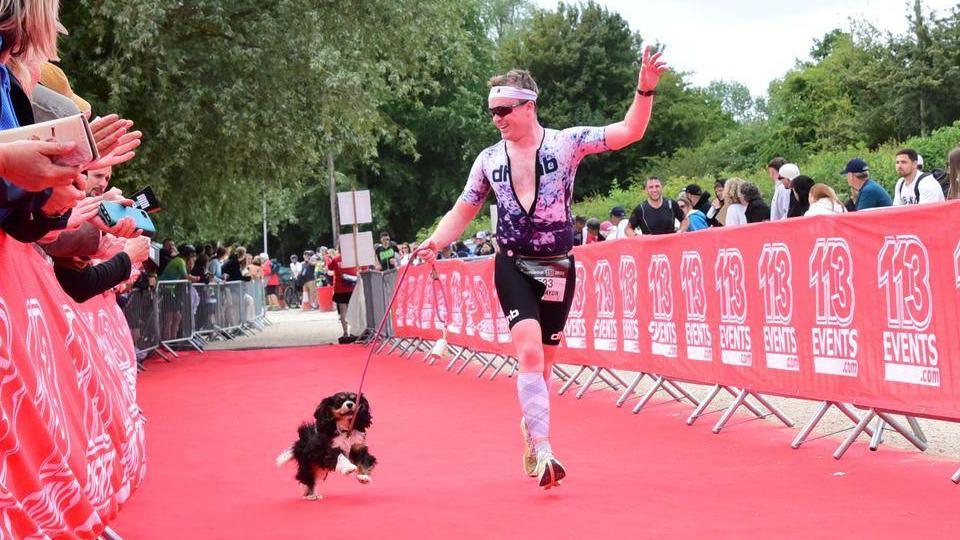 Ryan McCarthy crosses the finish line at an event with his dog Maisie.
