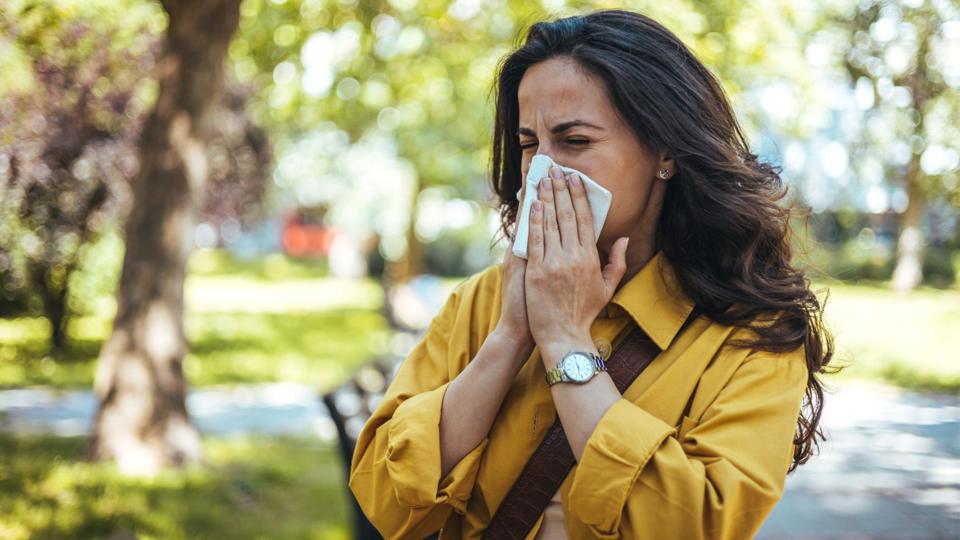 A woman blowing her nose outside.
