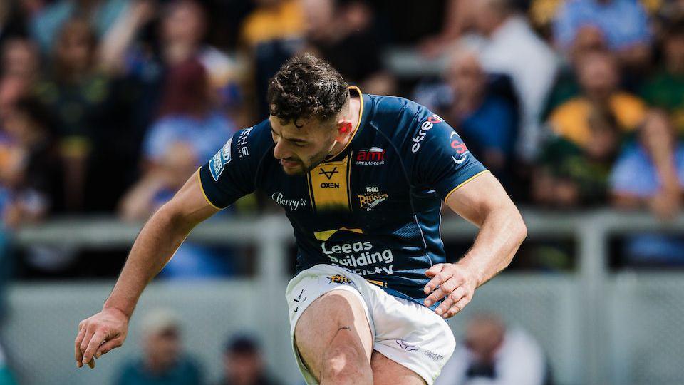 Leeds Rhinos' Jake Connor, with his head down, kicking a goal.