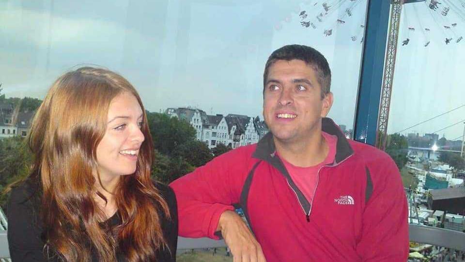 A smiling Trevor Bygate with daughter Chloe sat in a gondola chair lift as it moves over a town 