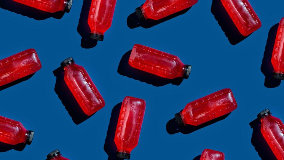 Bottles of cranberry juice dotted around on a dark blue background