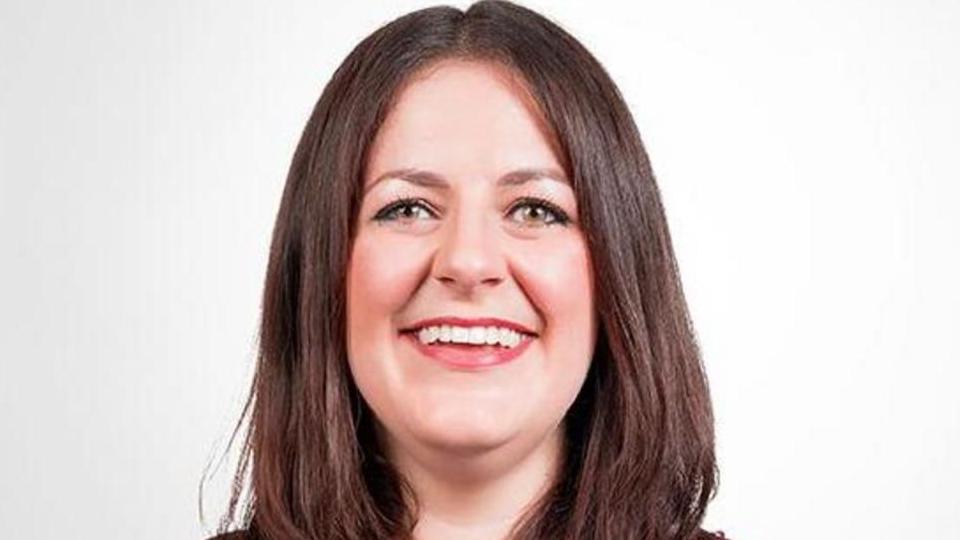 Laura Robertson smiles broadly. She has brown shoulder-length hair.