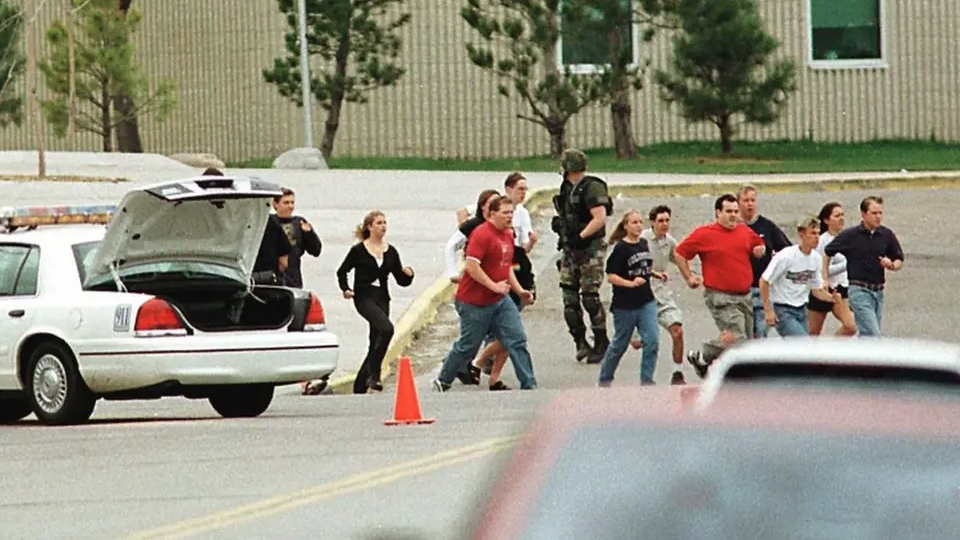 School pupils and staff are seen running from the school with an armed soldier