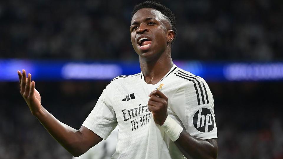 Vinicius Jr stands with one arm outstretched