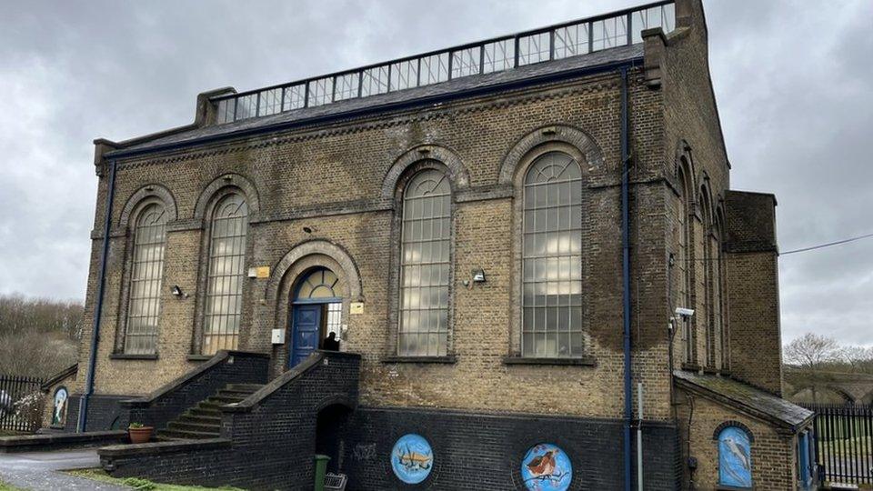 The water pump house at Davy Down, a high-ceiling, dark brick building with four arched windows and an arched entrance