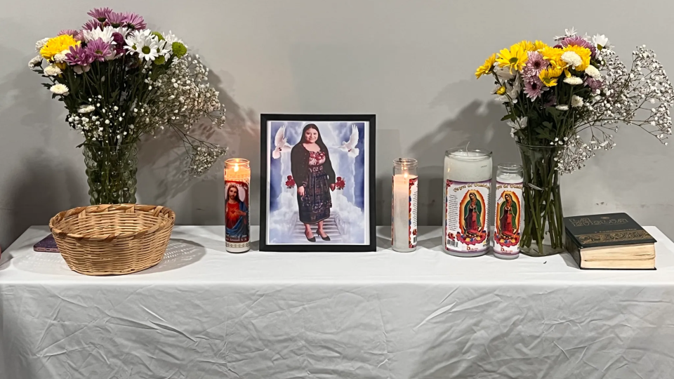 A photo of Maria Florinda Rios Perez is in a frame on a table with candles and flowers
