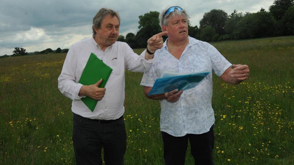 Councillors Graham Hill and David Vigar on Southwick Court Fields with clipboards and paperwork pointing into the distance