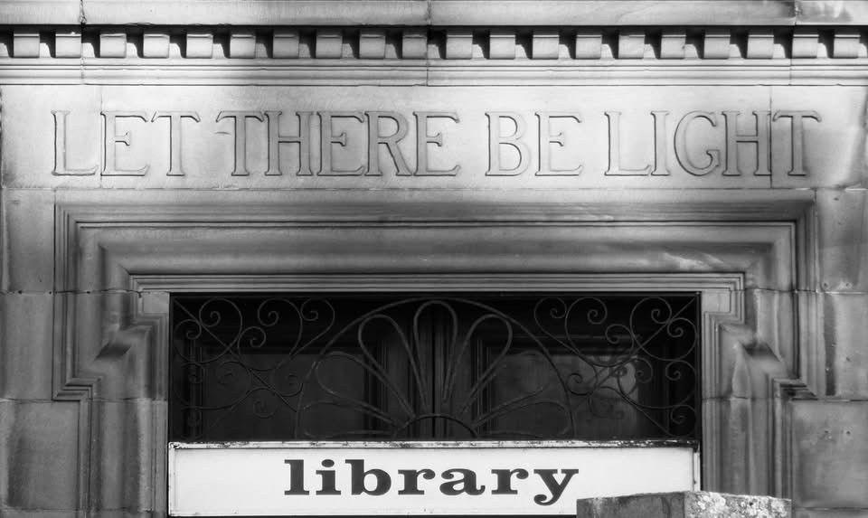 Black and white image of a library door which reads "Let there be light" at the top