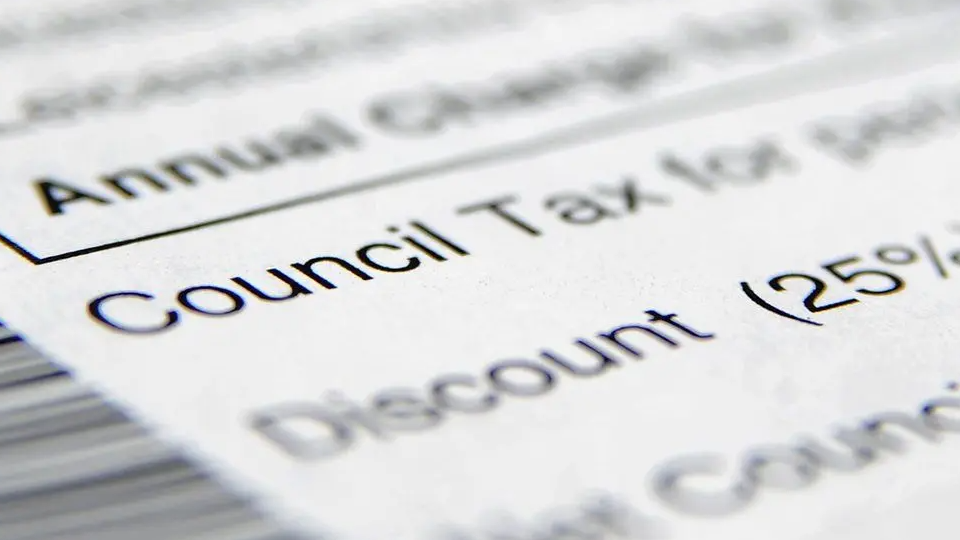 A close-up of a council tax statement on a table with most words blurred but "Council Tax" visible.