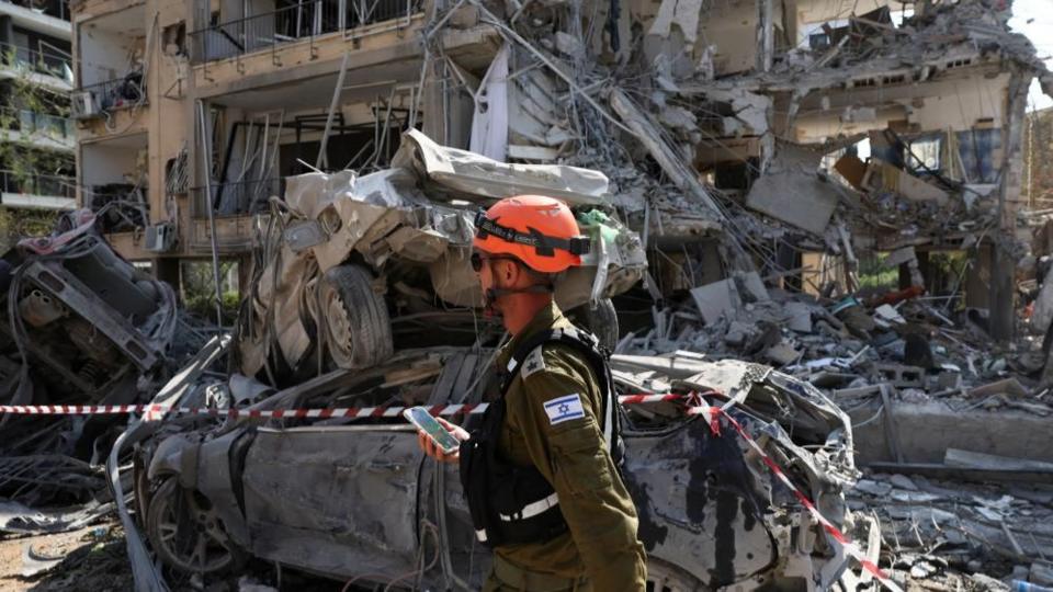 Rescue personnel walks past damaged vehicles at an impact site following missile attack from Iran on Israel, in Ramat Gan,