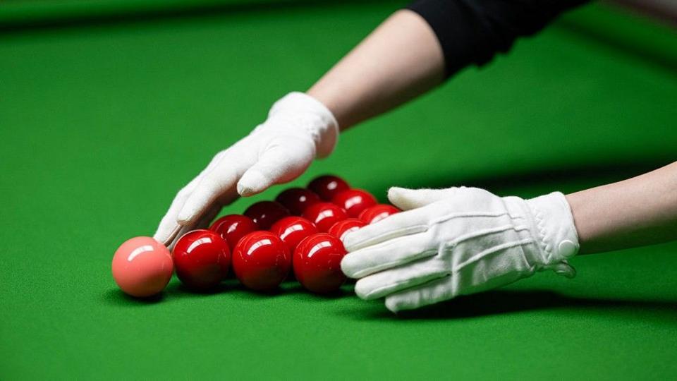 A snooker referee placing balls onto a table