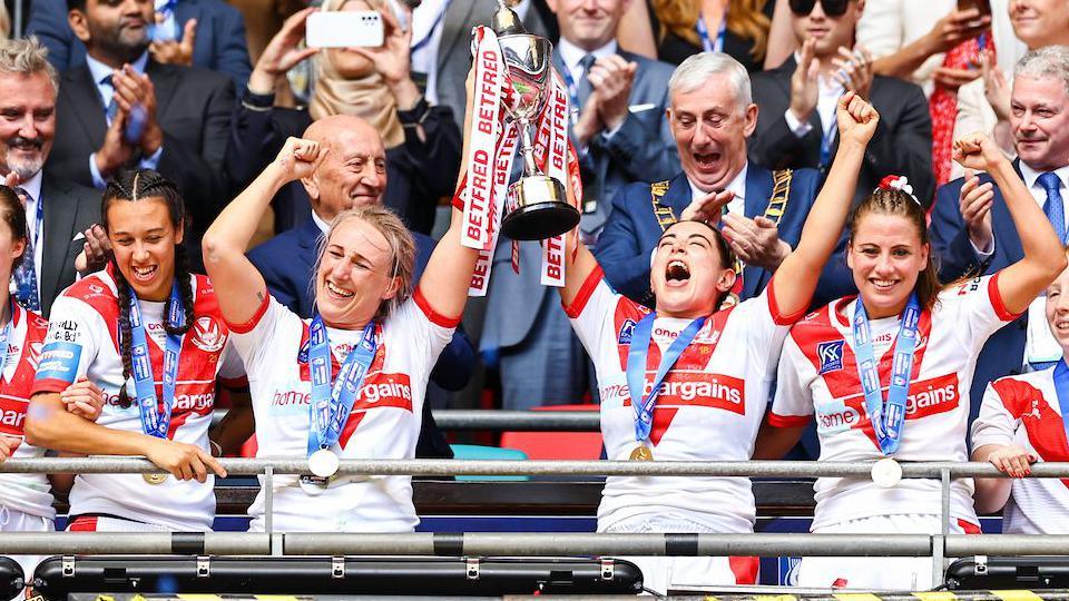 Jodie Cunningham and Emily Rudge of St Helens lift the Challenge Cup Trophy after victory over Leeds Rhinos in the 2023 Women's Challenge Cup final 