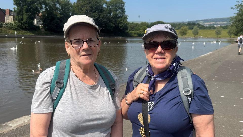 Sadie has a grey t-shirt and grey cap, while Anne has a blue t-shirt, scarf and light grey coloured cap.
