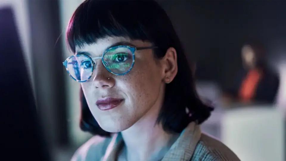 Woman wearing glasses looking at computer screen, which is reflecting in her glasses