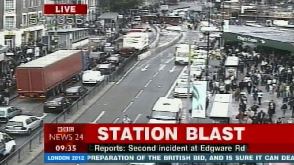 A photo of BBC News 24 TV channel at 0935 on the day of the blast. The caption says "station blast" and underneath "Reports: second incident at Edgware Rd". A large crowd can be seen outside Kings Cross overground station with traffic backed up on the opposite side of the road.