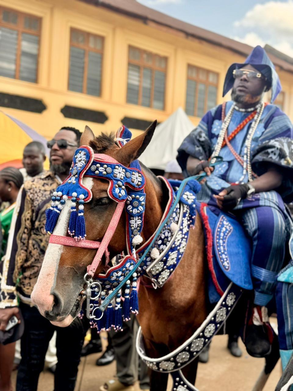 A man on a decorated horse dressed in blue brocade.