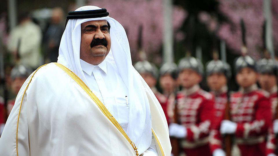 Hamad is seen wearing a white robe as uniformed military guards stand to attention behind him.