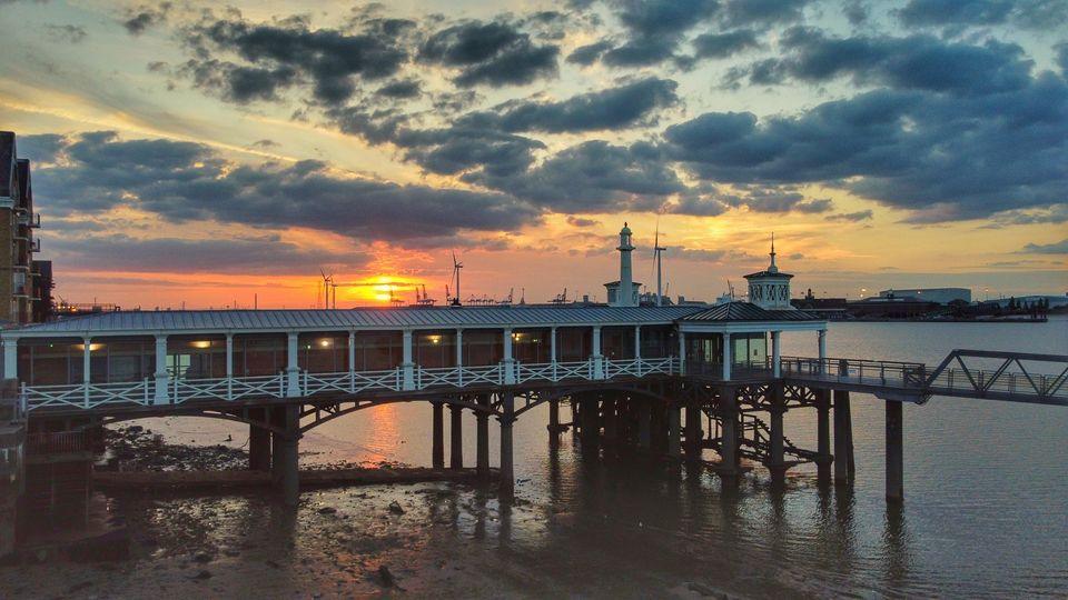 A pier in front of the sunsetting.