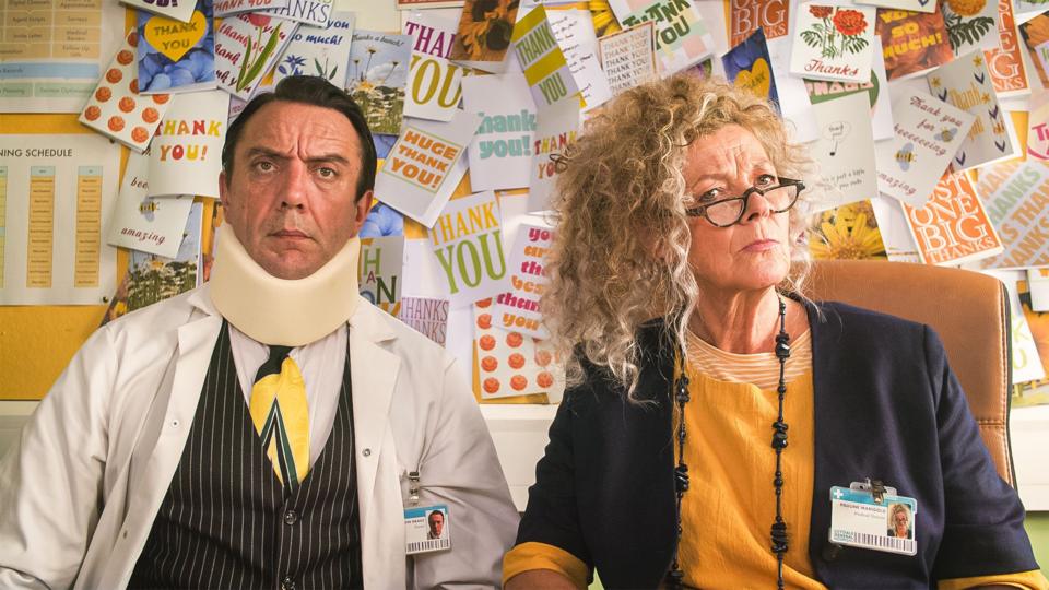 a man wearing a sponge neck brace is sitting next to a woman with curly hair and glasses, both looking confused