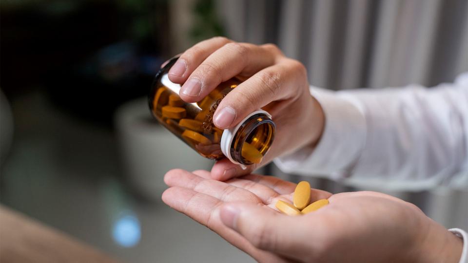 Close up of human hands tipping out pills from a jar.  (stock photo)