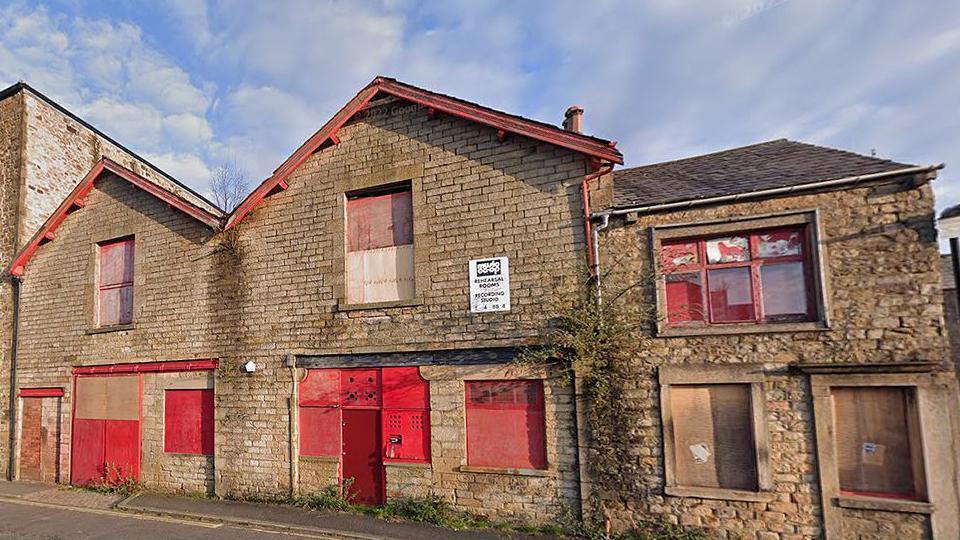 Empty building on Lodge Street, Lancaster, boarded up with red doors and shutters on the windows