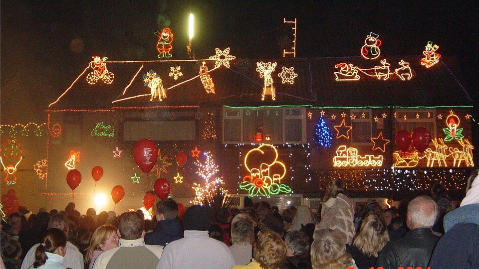 Exterior shot of a house with elaborate Christmas lights and a crown outside 