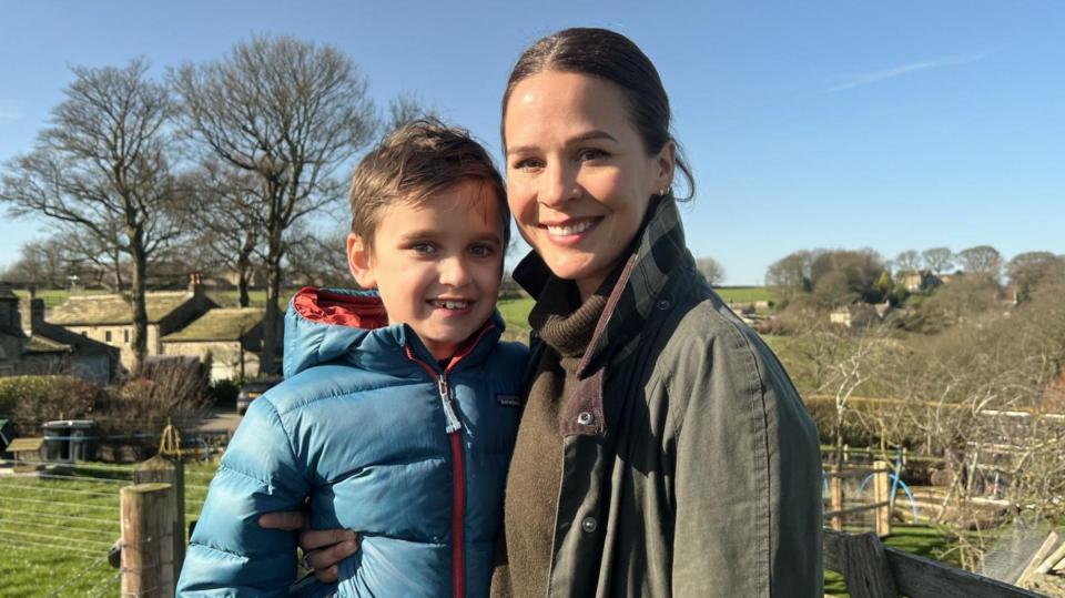 Freddie and his mum, Lauren, stand in the sunshine in fields near their home in Huddersfield