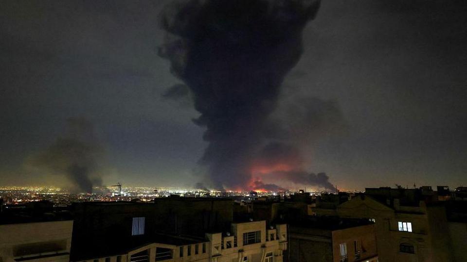 Thick black smoke rises over the skyline of Tehran