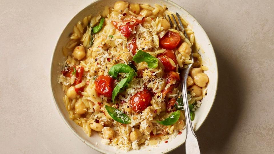 A bowl with orzo pasta, chickpeas, cherry tomatoes and fresh basil