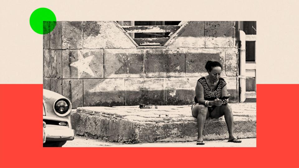 A woman looks at her phone on a street in Havana
