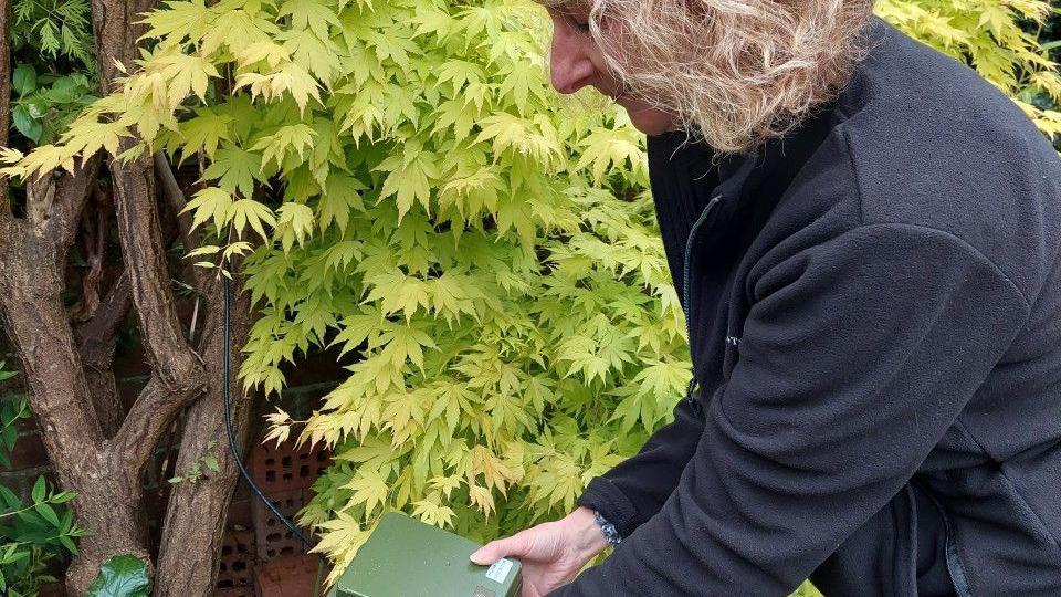 Lindsay Mahon holding a bat detector in a garden