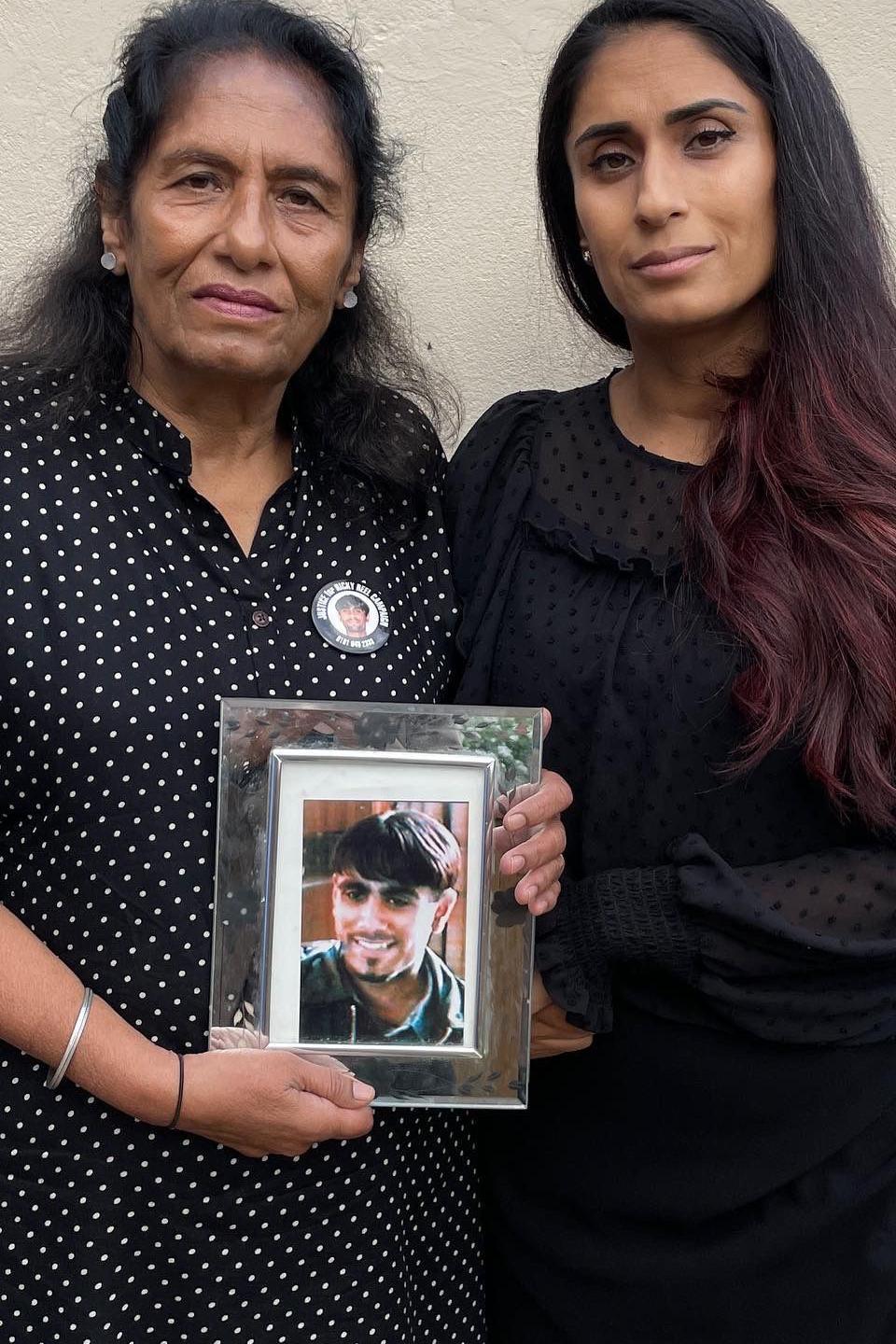 older woman and young woman looking to camera holding a framed photo