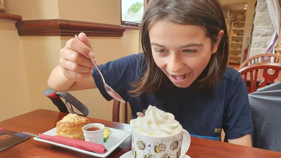 Finn eating in a cafe, he is excited by a hot chocolate with whipped cream and about to dig in with his spoon