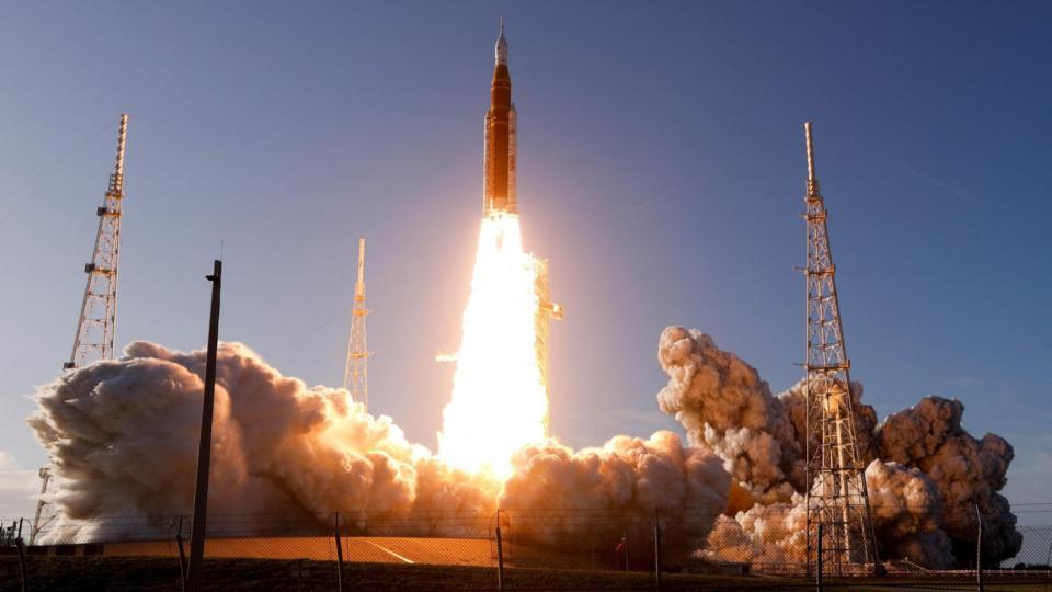 Rocket takes off from launch pad with huge trail of flames and smoke behind it