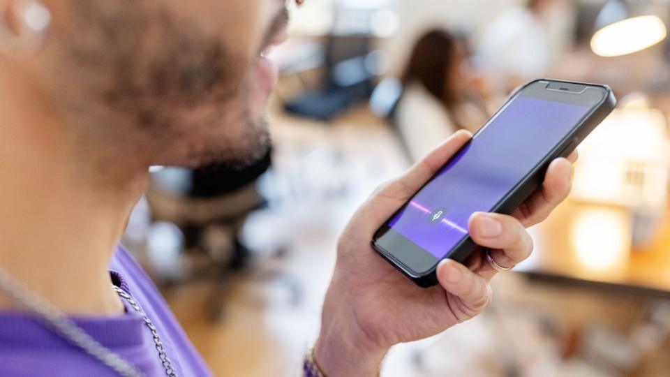 Close-up of man recording voice message on cellphone at office - stock photo