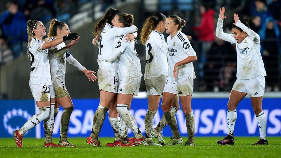 Real Madrid players celebrate in mud-splattered white kit