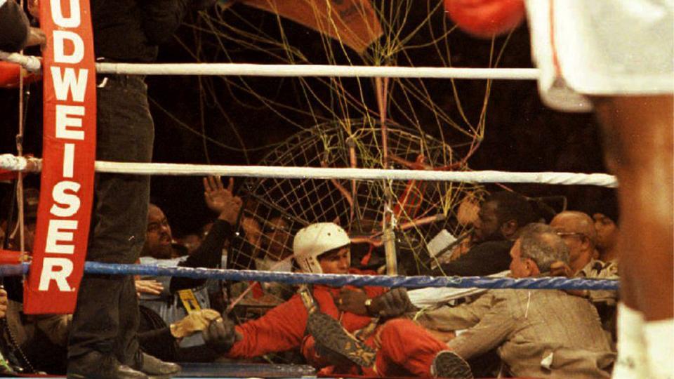 An unidentified parachutist lands on the ring apron 06 November 1993 after he fell during the seventh round of the heavyweight title fight between Evander Holyfield and Riddick Bowe.