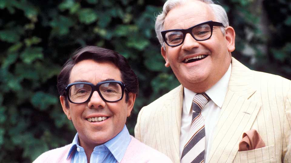 A close up of the Two Ronnies, both of whom are wearing glasses.